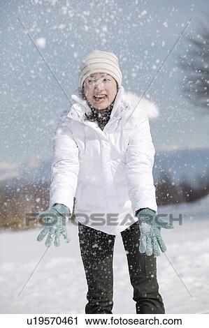 Stock Image - Young woman playing with snow. Fotosearch