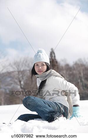 Stock Image - Young woman sitting in snow. Fotosearch