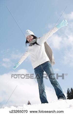 Stock Image - Young woman standing in snow. Fotosearch