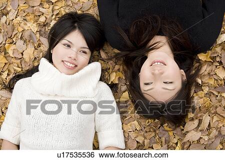 Stock Photograph - Two young women lying on fallen leaves. Fotosearch