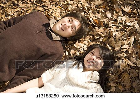 Young couple lying on fallen leaves View Large Photo Image Stock Image - Young couple lying on fallen leaves. Fotosearch
