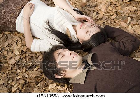 Stock Photo - Young couple lying on fallen leaves. Fotosearch