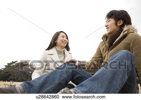 Stock Image - Young couple sitting on ground. Fotosearch