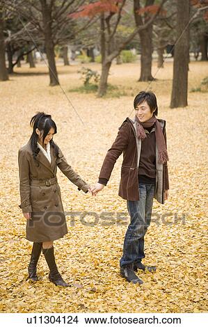 Young couple walking on fallen leaves View Large Photo Image Picture - Young couple walking on fallen leaves. Fotosearch