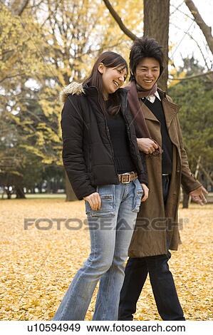 Young couple walking on fallen leaves View Large Photo Image Stock Photo - Young couple walking on fallen leaves. Fotosearch