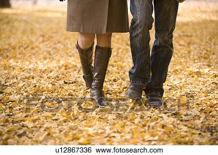 Stock Photograph - Young couple walking on fallen leaves. Fotosearch