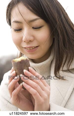 Stock Photo - Young woman eating sweet potato. Fotosearch
