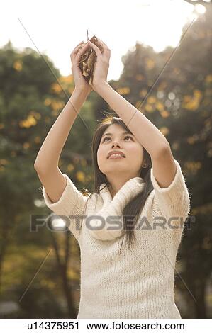 Stock Image - Young woman holding fallen leaves. Fotosearch