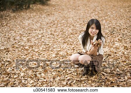 Stock Image - Young woman holding fallen leaves. Fotosearch