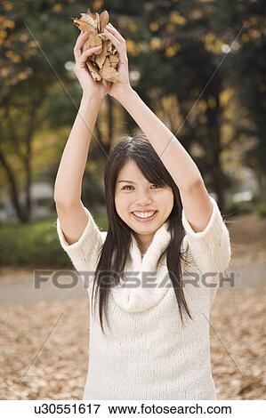 Stock Photo - Young woman holding fallen leaves. Fotosearch