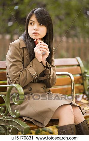 Young woman sitting on bench View Large Photo Image Stock Image - Young woman sitting on bench. Fotosearch