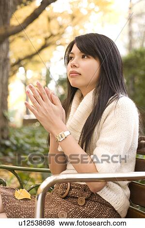 Stock Photo - Young woman sitting on bench. Fotosearch