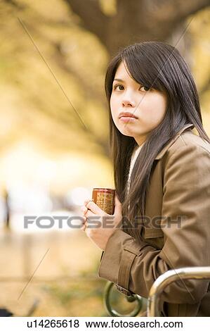 Stock Photo - Young woman sitting on bench. Fotosearch
