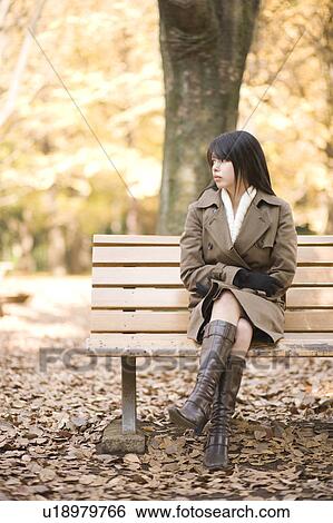 Stock Photograph - Young woman sitting on bench. Fotosearch
