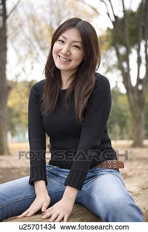 Young woman sitting on log View Large Photo Image Picture - Young woman sitting on log. Fotosearch