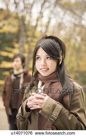 Young woman smiling, boyfriend in background View Large Photo Image Stock Photograph - Young woman smiling, boyfriend in background. Fotosearch