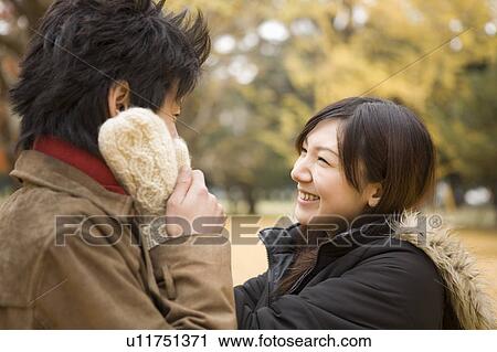 Stock Image - Young woman touching man's cheeks. Fotosearch