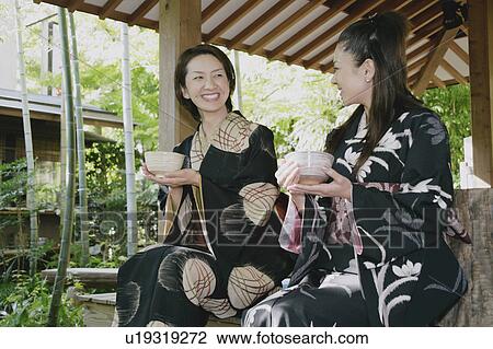 Stock Image - Two young women in kimono holding tea cup. Fotosearch