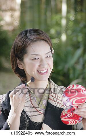 Stock Photography - Young woman in kimono applying make-up. Fotosearch