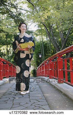 Young woman in kimono crossing bridge View Large Photo Image Stock Image - Young woman in kimono crossing bridge. Fotosearch