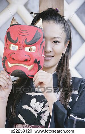 Young woman in kimono holding mask up to face View Large Photo Image Stock Image - Young woman in kimono holding mask up to face. Fotosearch