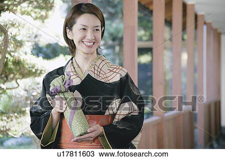 Young woman in kimono holding wrapped gift View Large Photo Image Stock Image - Young woman in kimono holding wrapped gift. Fotosearch