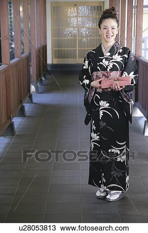 Stock Image - Young woman in kimono holding wrapped gift. Fotosearch