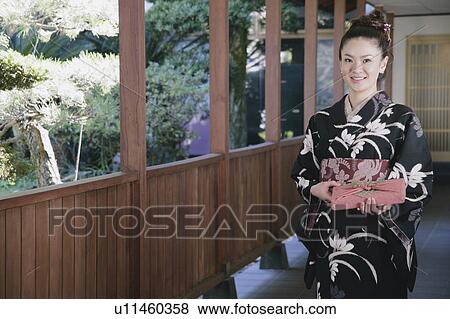 Young woman in kimono holding wrapped gift View Large Photo Image Stock Photo - Young woman in kimono holding wrapped gift. Fotosearch