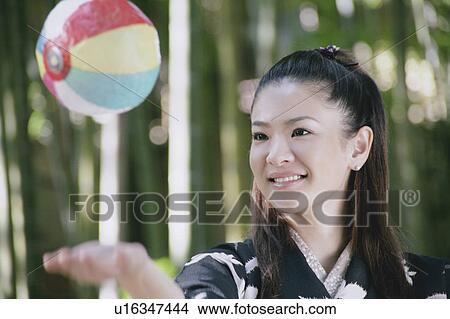 Picture - Young woman in kimono playing with paper balloon. Fotosearch