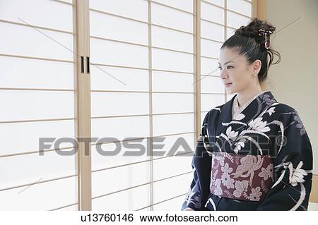 Stock Photograph - Young woman in kimono sitting on floor. Fotosearch