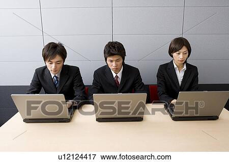 Three young business people using computers View Large Photo Image Stock Photo - Three young business people using computers. Fotosearch