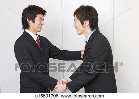 Two young businessmen shaking hands View Large Photo Image Stock Photograph - Two young businessmen shaking hands. Fotosearch