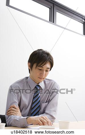 Young businessman looking at document View Large Photo Image Stock Photo - Young businessman looking at document. Fotosearch
