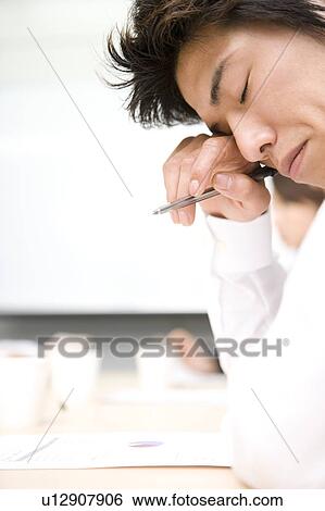 Young businessman rubbing eye View Large Photo Image Stock Photograph - Young businessman rubbing eye. Fotosearch