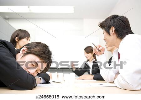 Stock Photography - Young businessman sleeping during meeting. Fotosearch