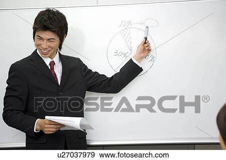 Stock Photo - Young businessman standing in front of whiteboard. Fotosearch