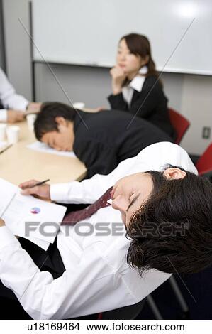 Picture - Young businessmen sleeping during meeting. Fotosearch