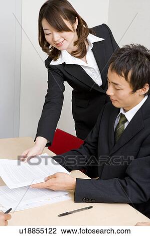 Stock Image - Young businesswoman giving document to colleague. Fotosearch