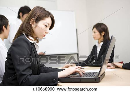 Stock Image - Young businesswoman using laptop. Fotosearch