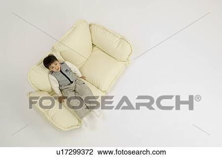 Stock Image - Boy sitting on sofa. Fotosearch