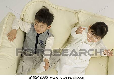 Brother and sister sitting on sofa View Large Photo Image Stock Photography - Brother and sister sitting on sofa. Fotosearch