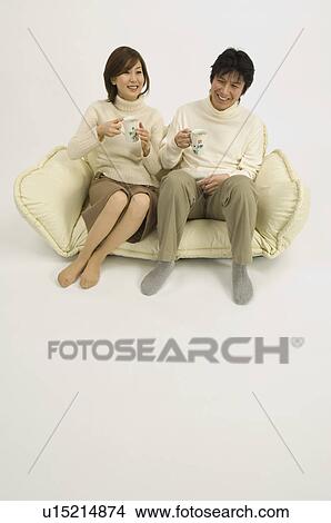 Picture - Couple drinking coffee on sofa. Fotosearch