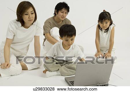 Family watching son use computer View Large Photo Image Stock Photo - Family watching son use computer. Fotosearch