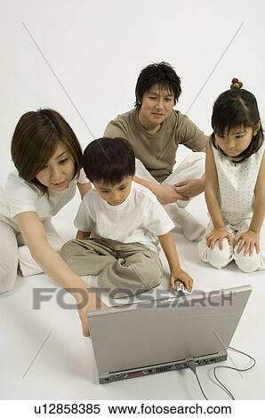 Stock Photography - Family watching son use computer. Fotosearch