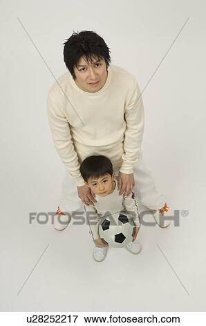 Stock Photo - Father and son looking up at camera. Fotosearch