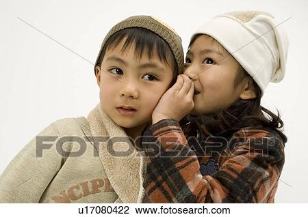 Stock Image - Girl whispering to her brother. Fotosearch