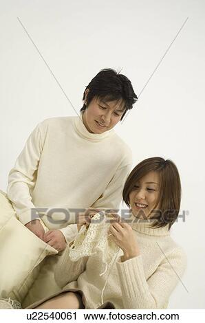 Stock Image - Husband watching wife knit. Fotosearch