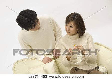 Stock Image - Husband watching wife knit. Fotosearch