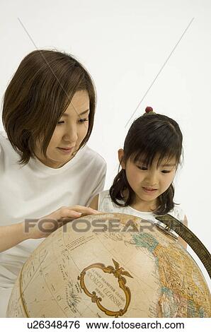 Mother and daughter looking at globe View Large Photo Image Stock Photograph - Mother and daughter looking at globe. Fotosearch