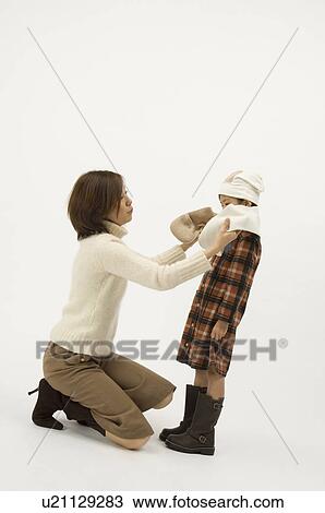 Stock Image - Mother putting scarf on daughter. Fotosearch
